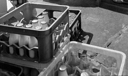 Fotoausschnitt: Getränkekästen mit Milchflaschen am Stand eines Protestverkaufs von Molkereiprodukten vor dem Buna-Kulturhaus X 50, 12. Juli 1990
