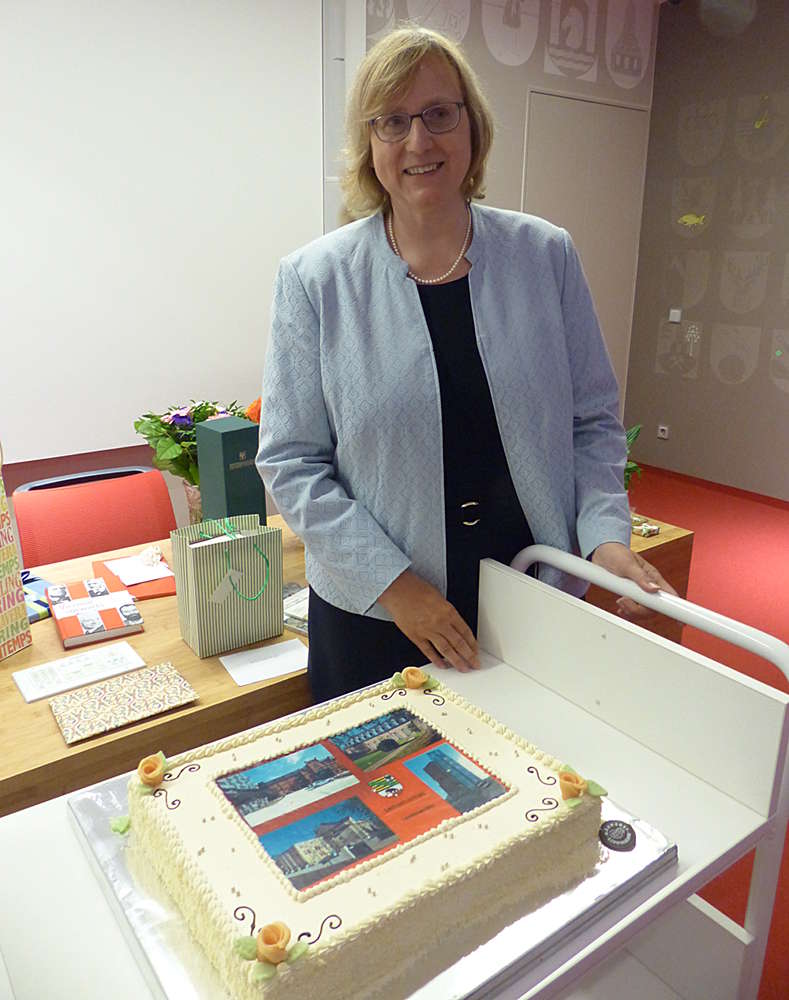 Abbildung Prof. Dr. Ulrike Höroldt mit einem Präsent ihrer Mitarbeiter, eine Torte mit allen vier Standorten des Landesarchivs