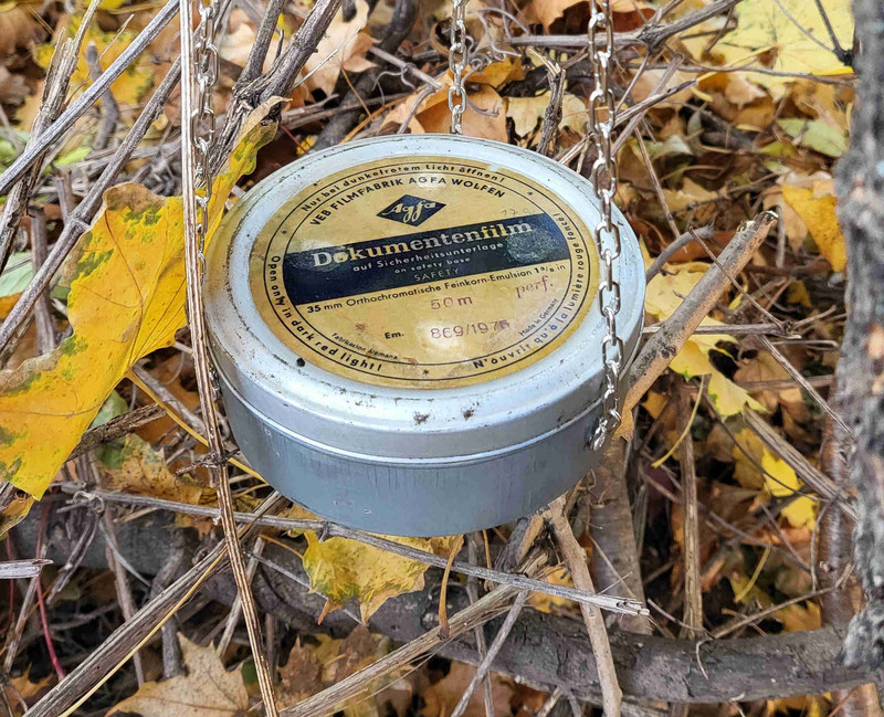 Die für den Cache ausgewählte Dose der VEB Filmfabrik AGFA Wolfen ist mit einer Kette an einem Baum befestigt. 